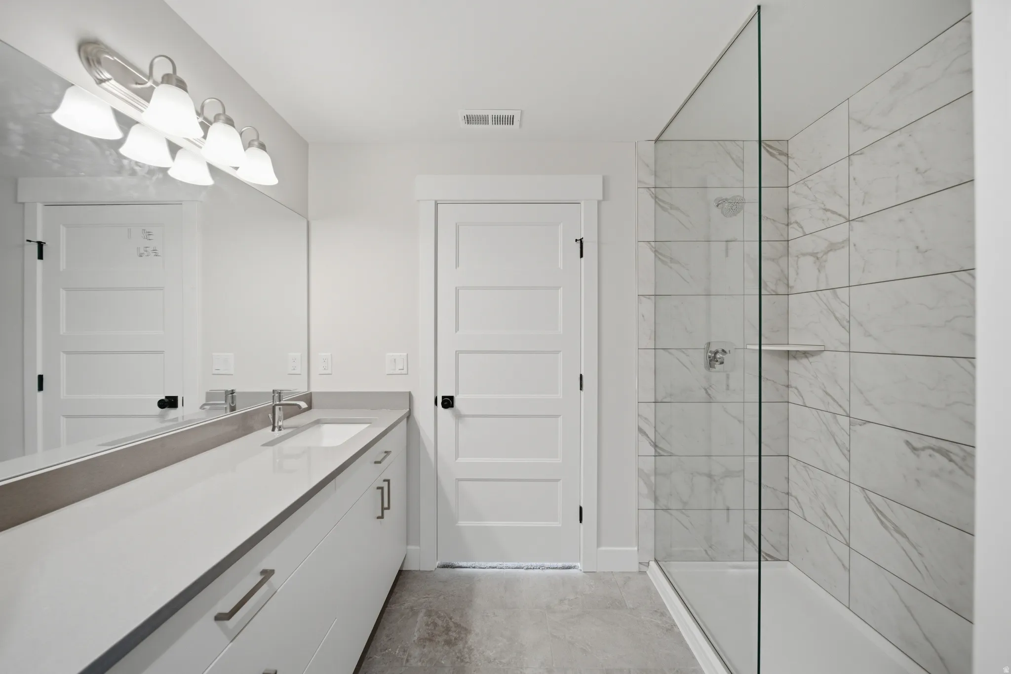 Contemporary bathroom featuring a spacious vanity with an undermount sink, a large mirror, and a wall-mounted light fixture