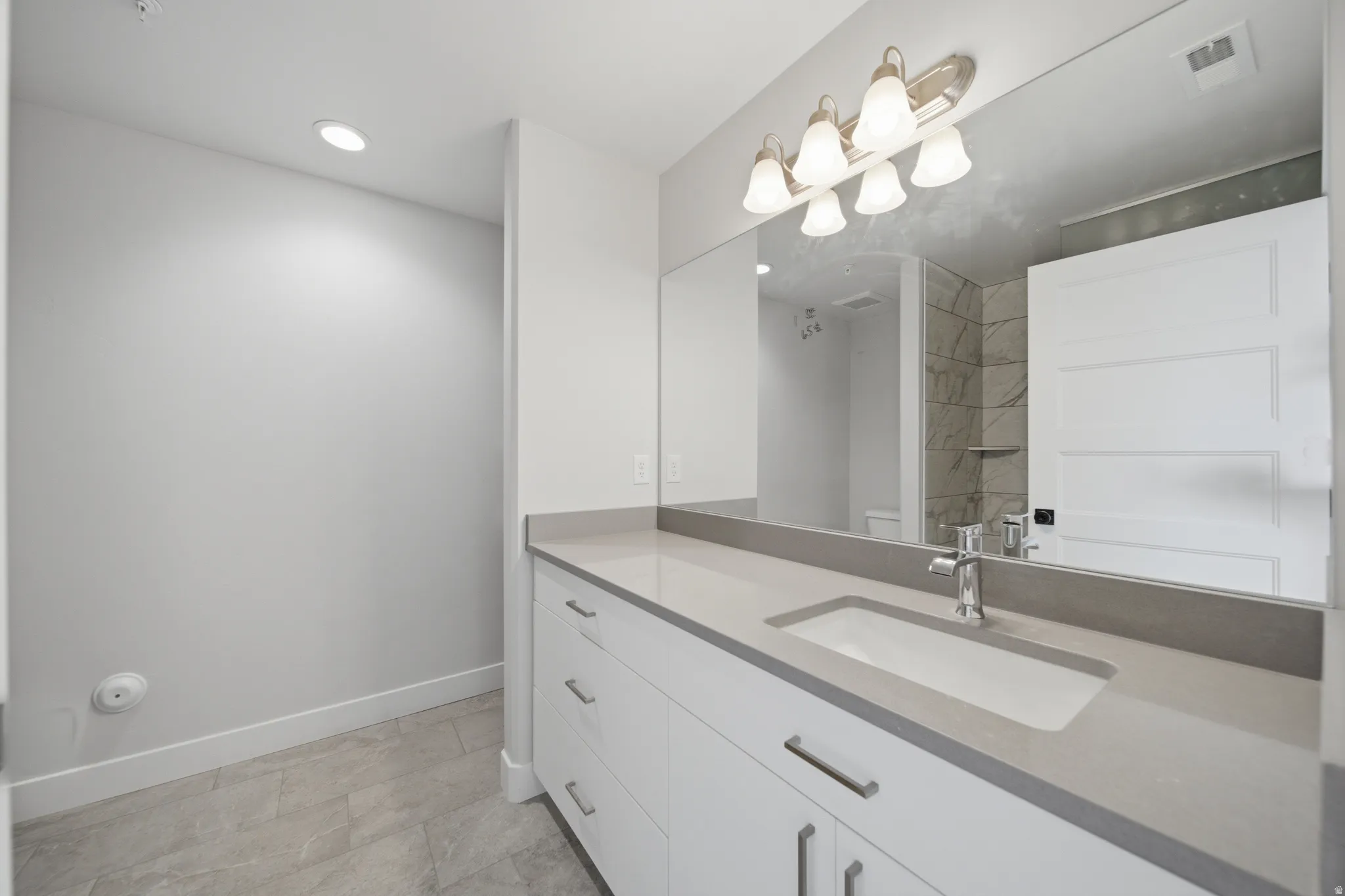 Modern bathroom vanity featuring a rectangular undermount sink set into a light-toned countertop