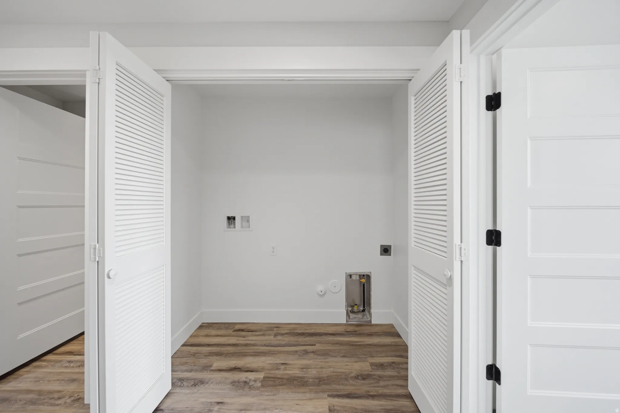 Dedicated laundry alcove featuring wood-finish flooring and bright white walls