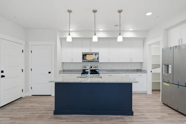 Kitchen featuring a central island with a contrasting navy base, light-toned countertop, and undermount sink