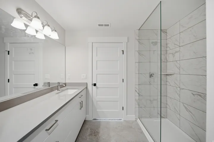 Contemporary bathroom featuring a spacious vanity with an undermount sink, a large mirror, and a wall-mounted light fixture