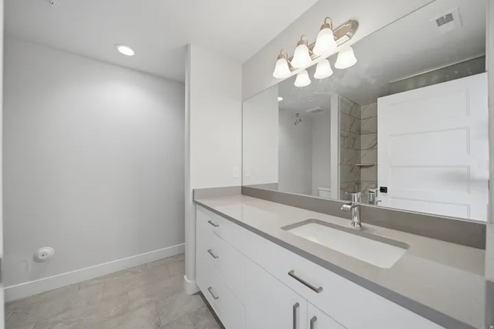 Modern bathroom vanity featuring a rectangular undermount sink set into a light-toned countertop