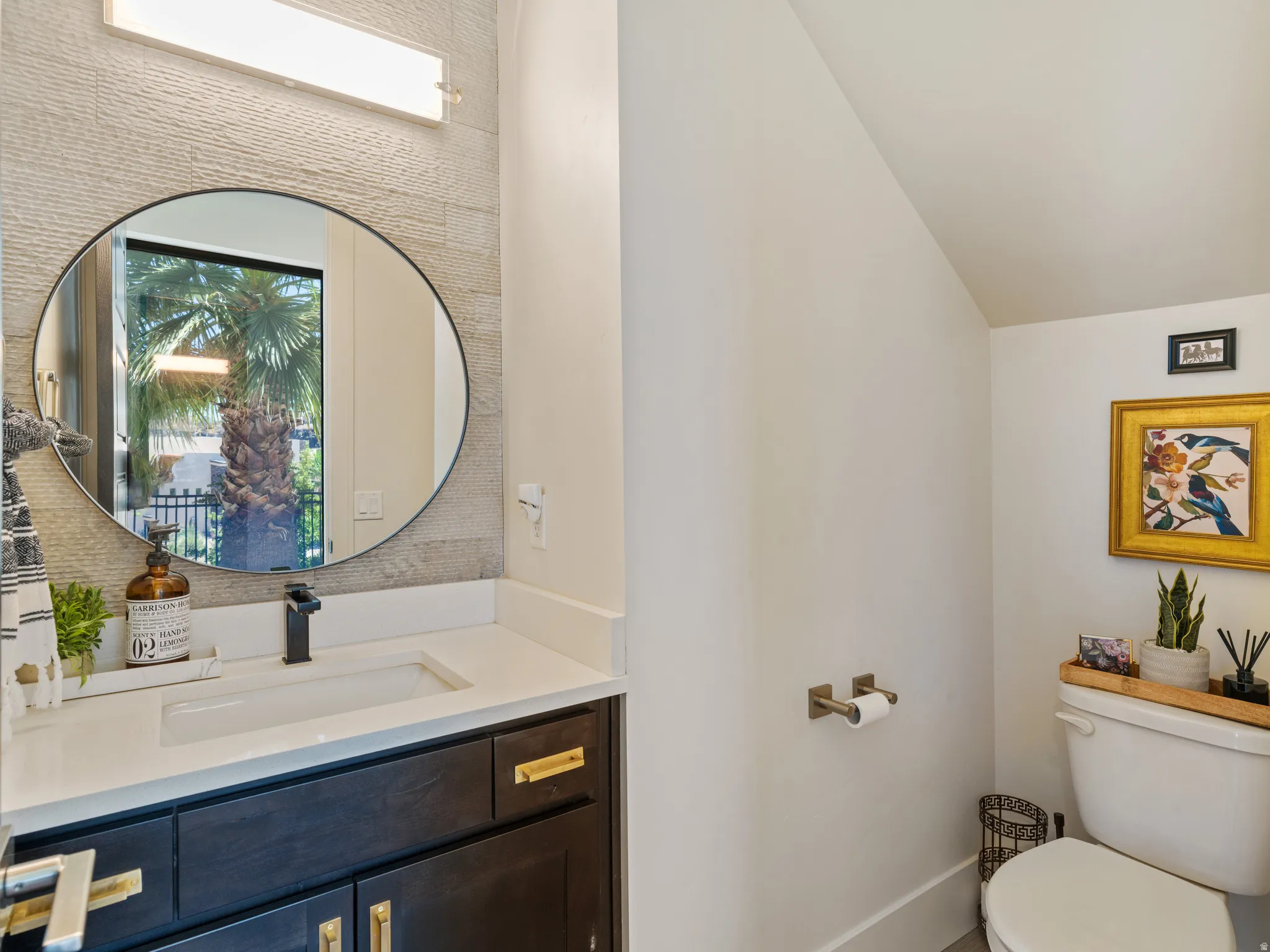 Vanity with white countertop, integrated sink, and matte black faucet with a tile accent wall.
