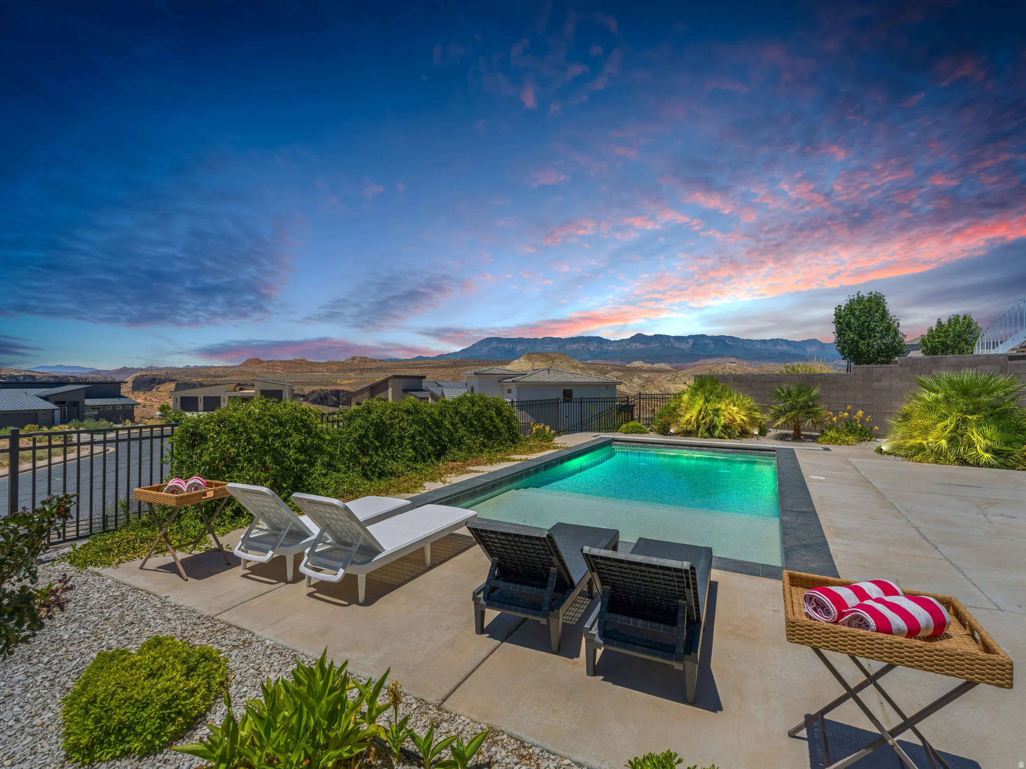 In-ground swimming pool with a concrete patio surround, bordered by gravel landscaping and mature plantings