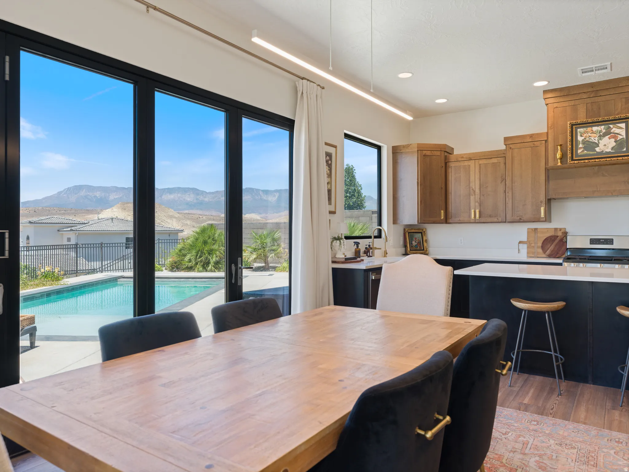 Bi-fold glass wall doors opening to a private swimming pool with mountain scenery