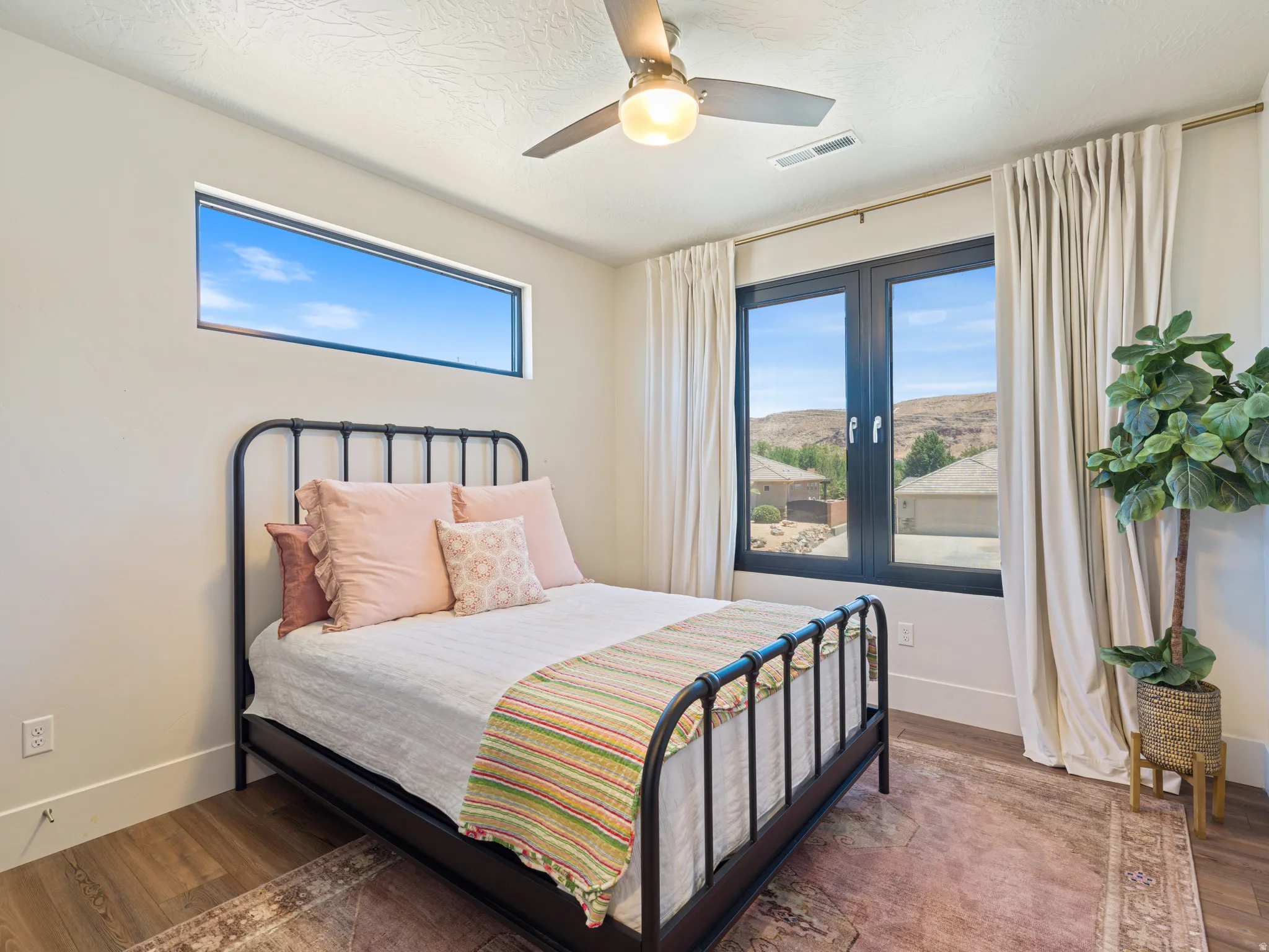 Expansive window views of distant hills,, a contemporary ceiling fan,all black windows and a high horizontal window