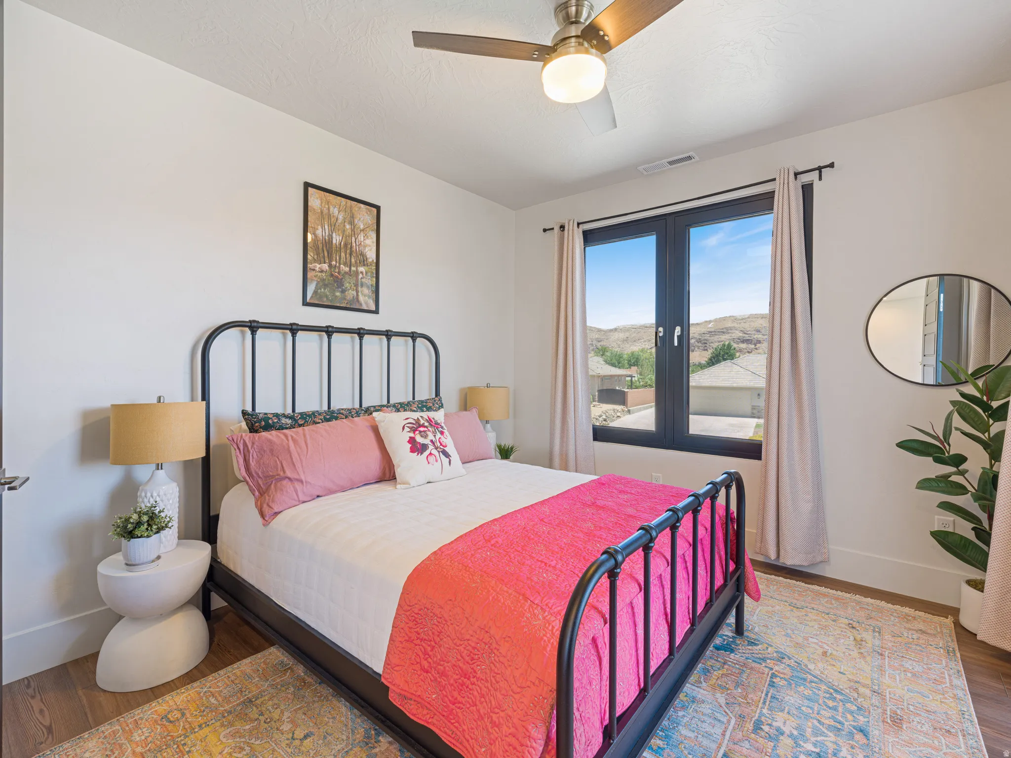 Bedroom featuring a window with a mountain backdrop a ceiling fan, and white walls