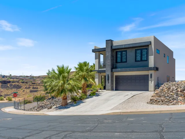 Contemporary-style residence featuring a stucco exterior with dark accent paneling, an integrated garage with a paneled door, and multiple large windows