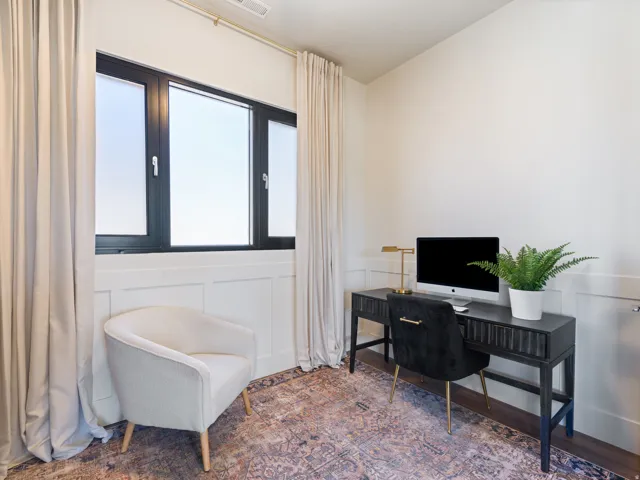Room featuring wainscoting details, dark-framed multi-pane windows, light-toned drapery