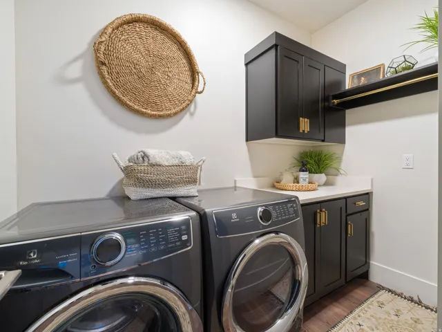 Laundry area featuring dark cabinetry with gold-toned hardware, a white countertop, and wood-finish flooring