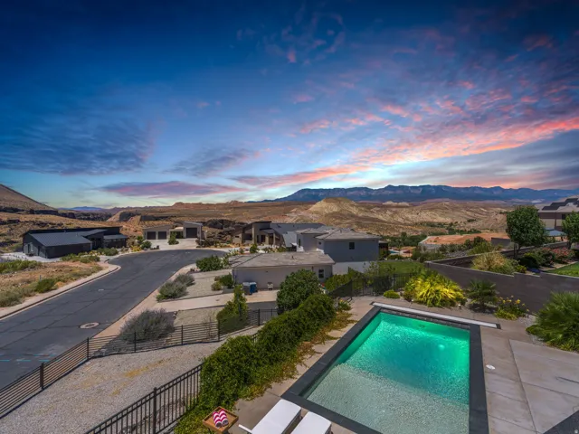 In-ground swimming pool with integrated steps and a surrounding concrete patio. View from the Deck