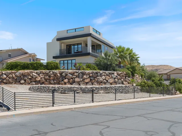 Contemporary multi-story residence featuring a stucco exterior, dark balcony railings, and extensive window placements
