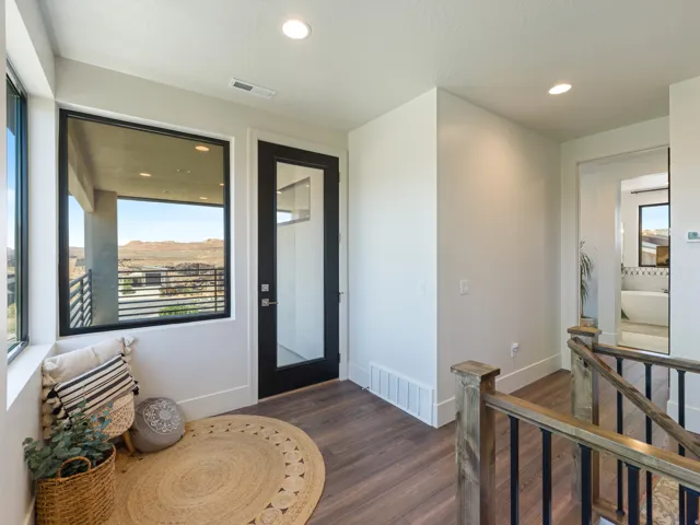 Second-story landing featuring large windows with black frames, and a modern glass-paneled door