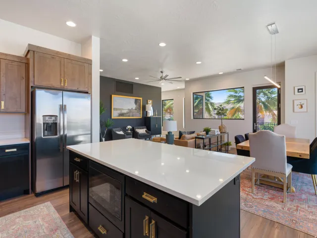Modern kitchen featuring a large island with a light-toned countertop, dark base cabinetry, and brass-tone hardware