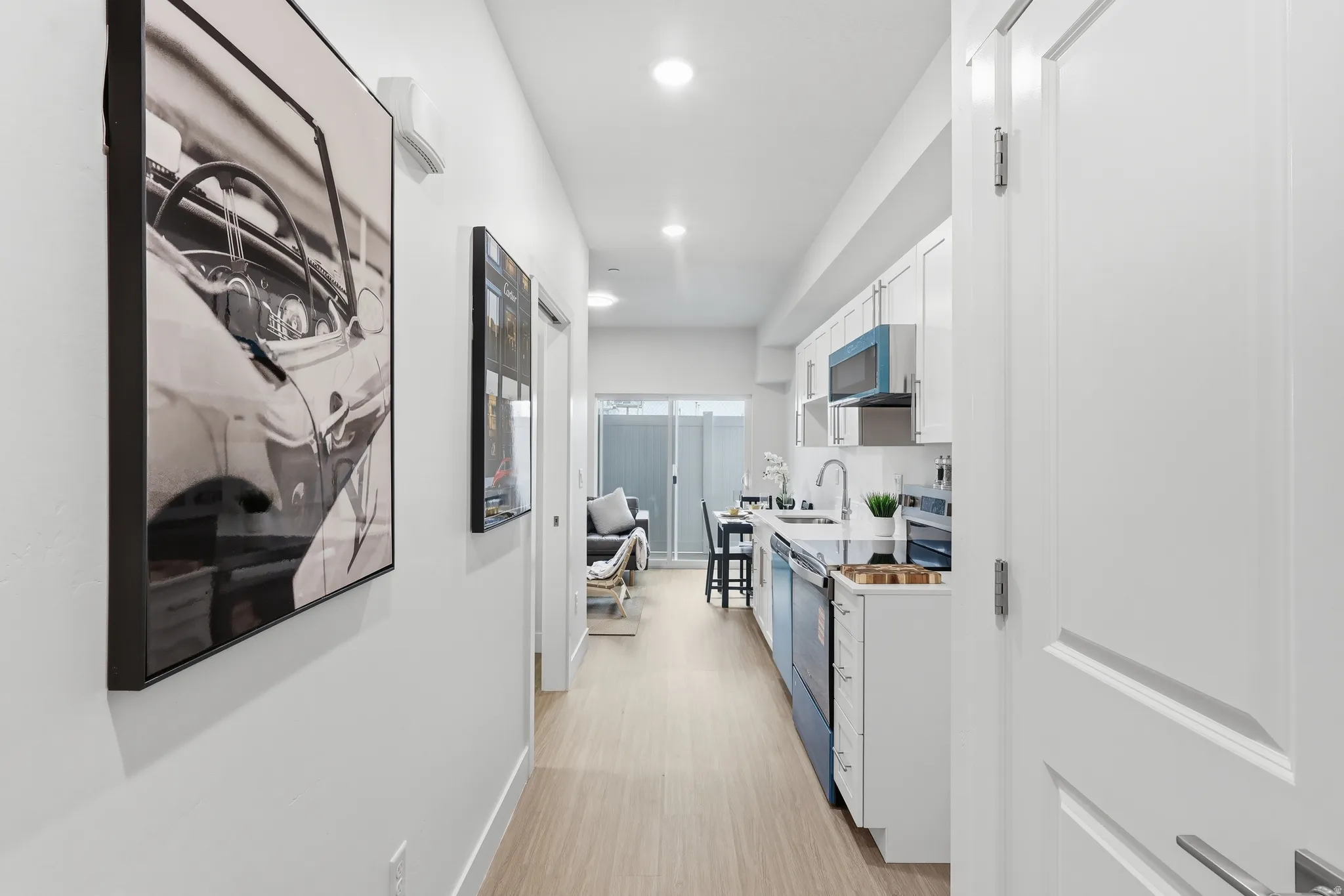 Contemporary kitchen featuring white cabinetry, light-colored wood-finish flooring, recessed lighting, stainless steel appliances, and a white countertop