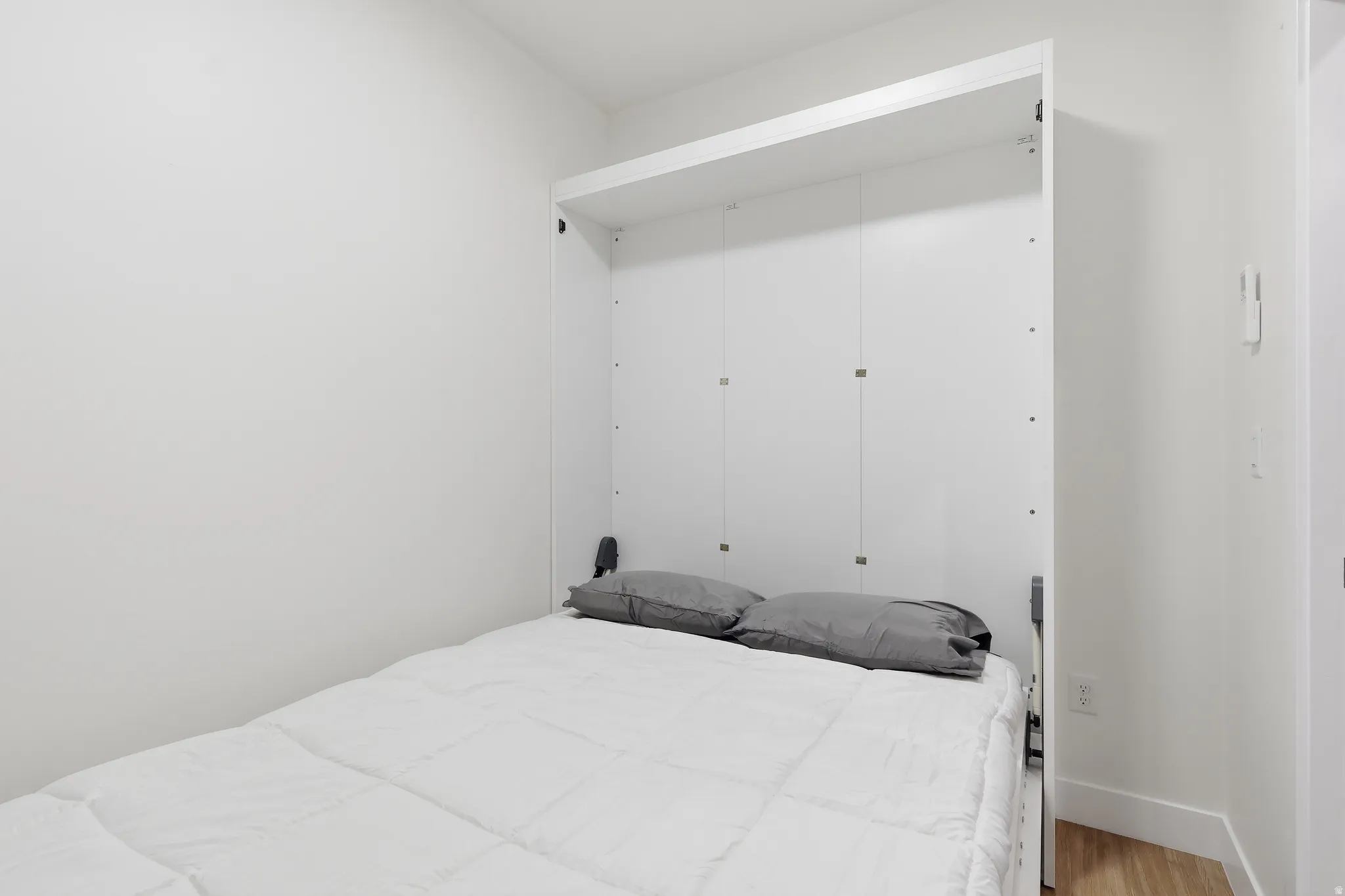 Integrated white wall bed with a light wood-finish flooring