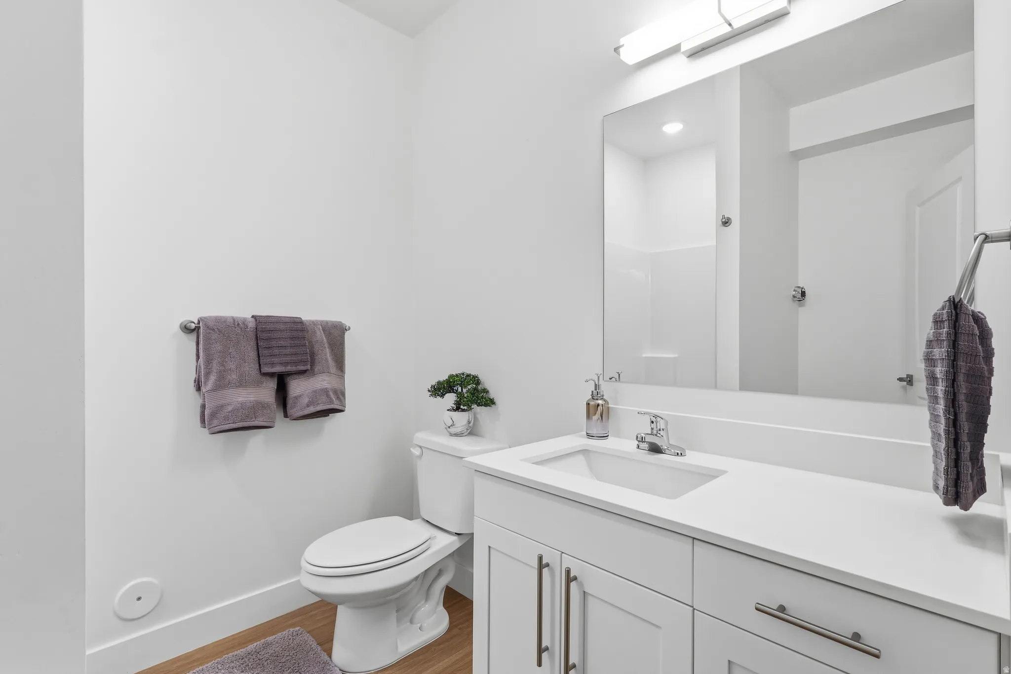 Bathroom featuring a white vanity with an integrated sink, polished chrome faucet, and expansive wall-mounted mirror