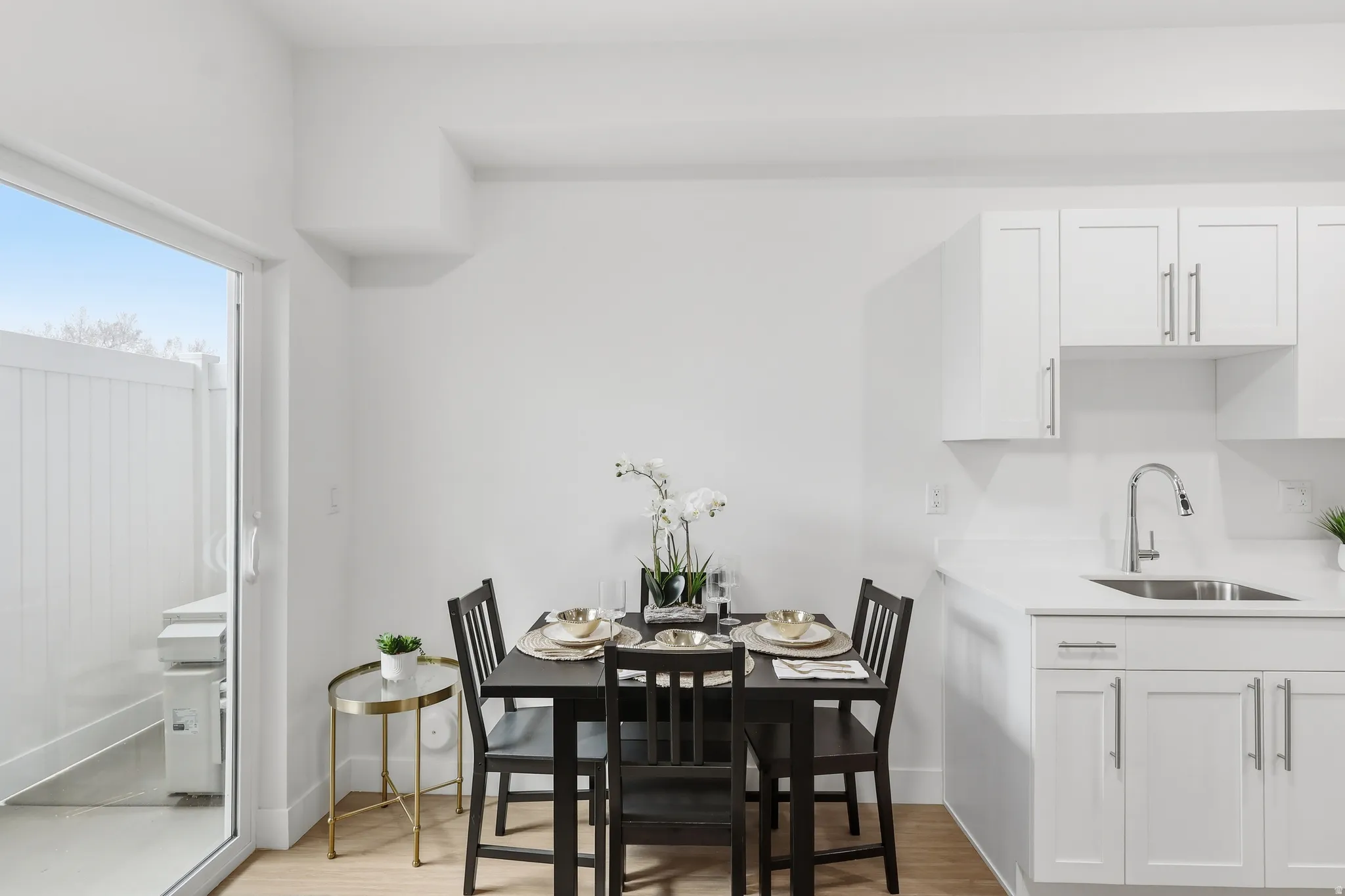 Compact dining area featuring wood-finish flooring, white walls, and a sliding glass door leading to an outdoor space