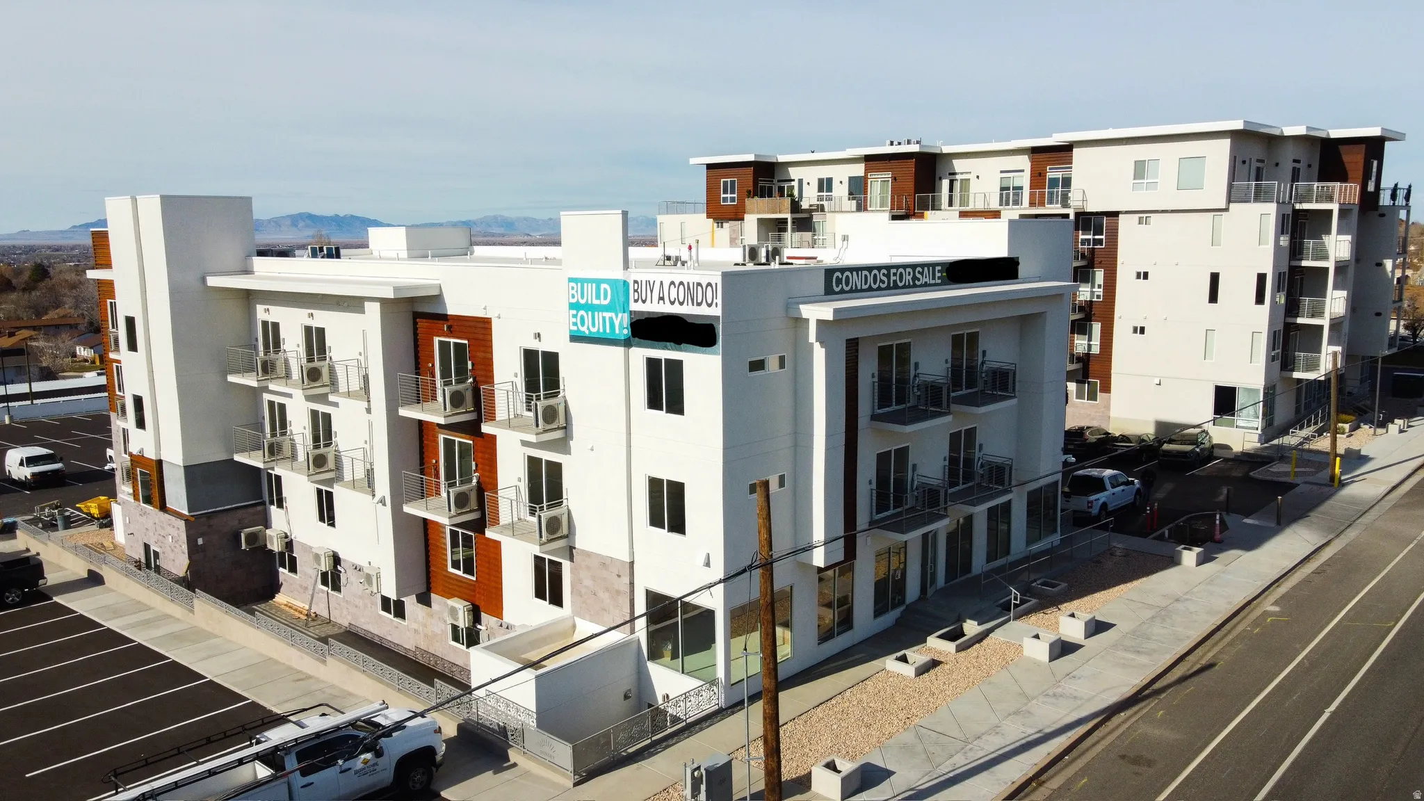 Contemporary multi-story building featuring white stucco, wood-finish paneling, and stone-finish accents