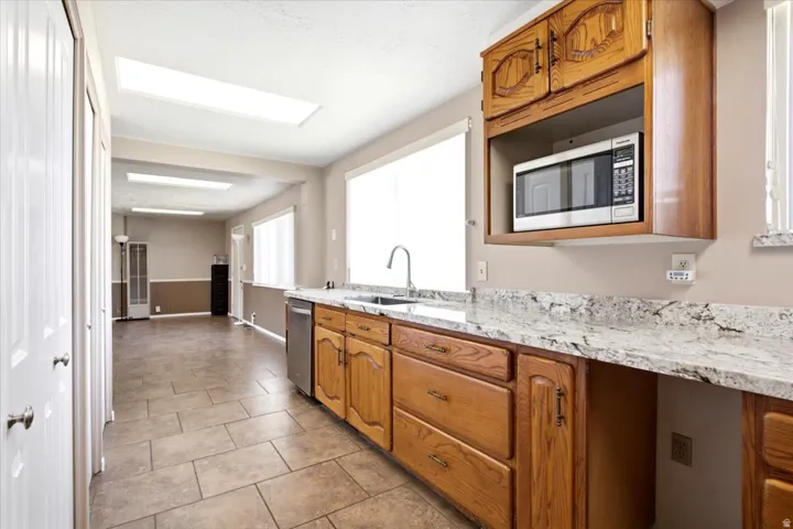 Kitchen featuring wood cabinetry, a stainless steel dishwasher, and a built-in microwave