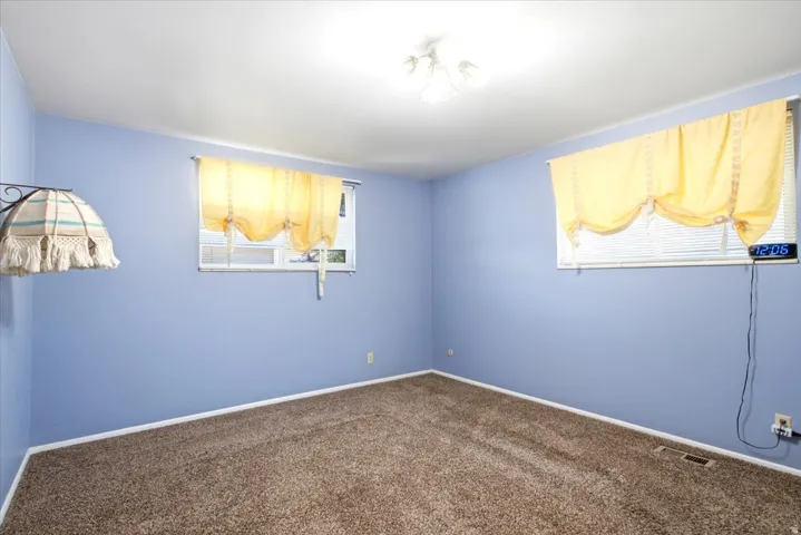 Room with wall-to-wall carpeting, light blue painted walls, and white baseboards