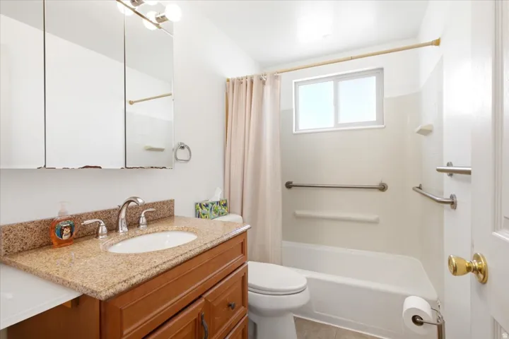 Bathroom featuring a single vanity with a granite-style countertop, an undermount sink, and chrome fixtures