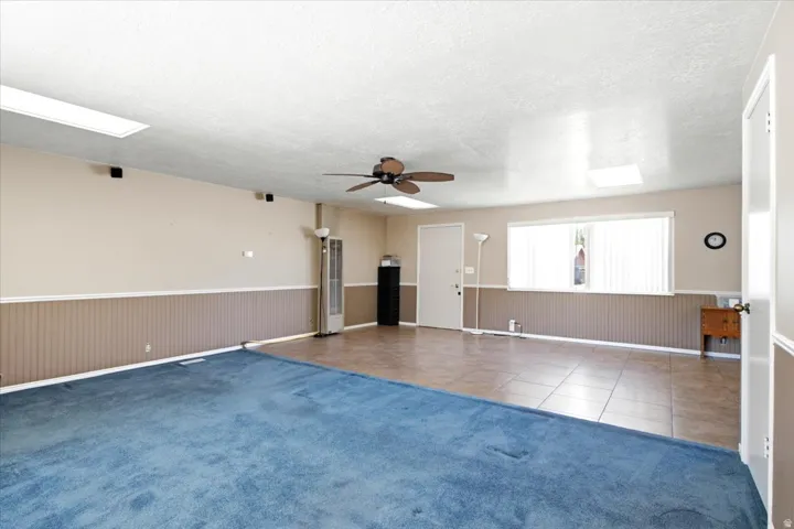 Open-concept room featuring a combination of blue carpeting and neutral-toned tile flooring