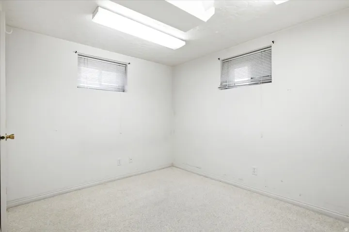 Room featuring two horizontal windows with blinds, wall-to-wall carpeting, and baseboard trim