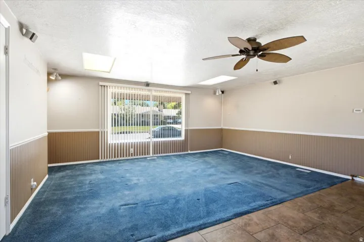 Spacious room featuring a large sliding glass door with vertical blinds, providing ample natural light