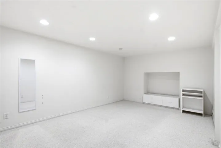 Spacious room featuring light-colored carpeting, recessed lighting, and a built-in media niche with integrated cabinetry