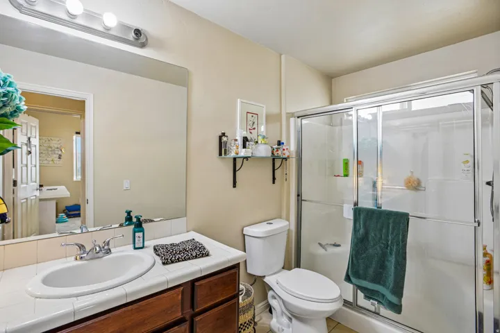 Bathroom featuring a single vanity with wood cabinetry, a tiled countertop, and an oval sink