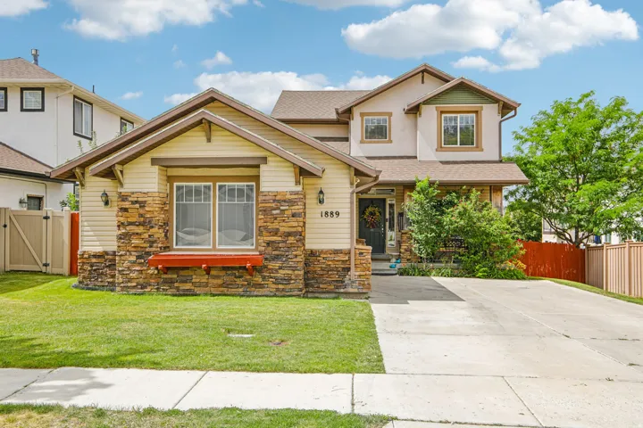 Front exterior featuring stone and siding finishes, a well-maintained lawn, a concrete driveway, a front porch, and a privacy fence