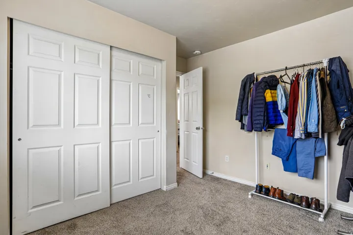 Room featuring a double sliding door closet with paneled doors and neutral carpet flooring