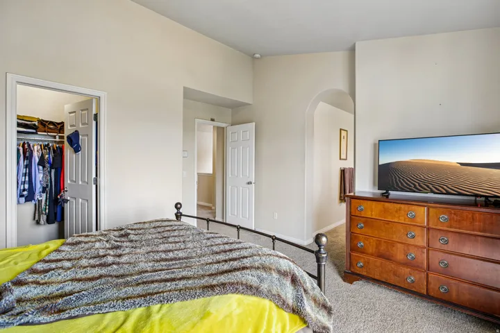 Neutral wall finishes, carpeted flooring, arched doorway, and white paneled doors