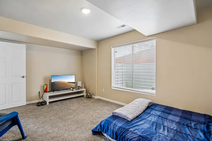 Carpeted room with a flush-mount ceiling light and a window with horizontal blinds
