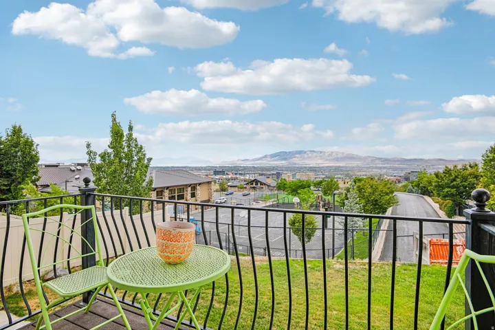 Balcony with black metal railings overlooking distant mountains and a residential area