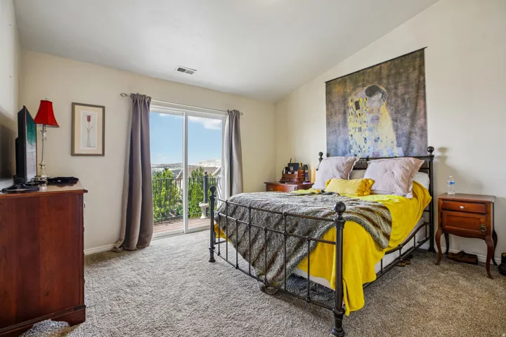 Bedroom featuring a sliding glass door to an exterior balcony, carpeted flooring, and neutral wall tones