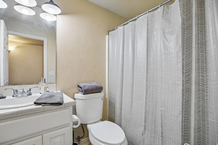 Bathroom featuring a white vanity with tile countertop, integrated sink, and chrome faucet
