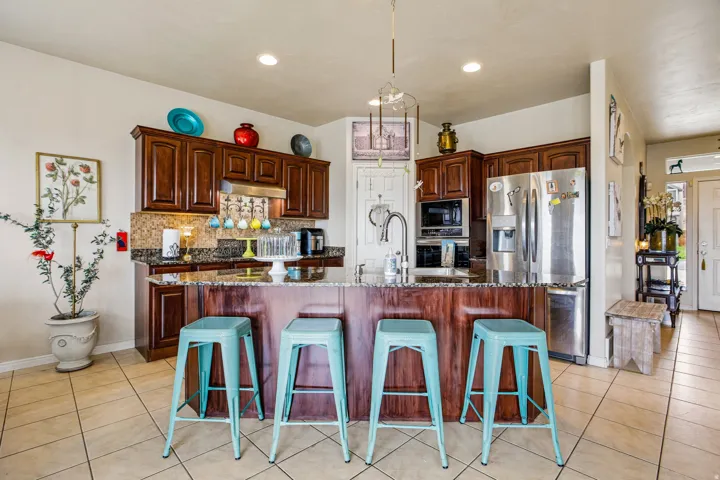 Kitchen featuring a large island with a breakfast bar, rich wood-finish cabinetry, granite countertops, and stainless steel appliances