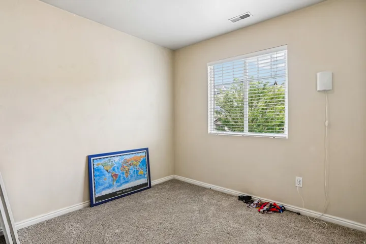 Room featuring a window with horizontal blinds, neutral-toned walls, and carpet flooring