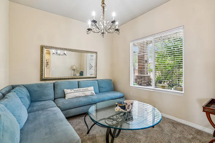 Living area featuring a chandelier light fixture, a large window with blinds, and neutral-toned wall paint