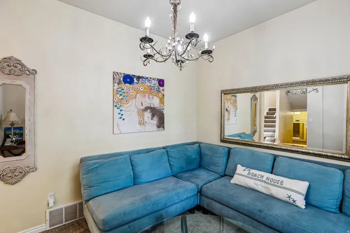 Interior room featuring a decorative chandelier with candelabra bulbs, light-toned wall paint, and a wall-mounted mirror with an ornate frame