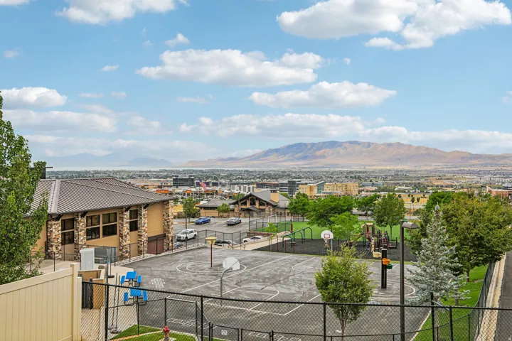 Expansive community recreation area featuring a paved basketball court, playground equipment, and turf lawn
