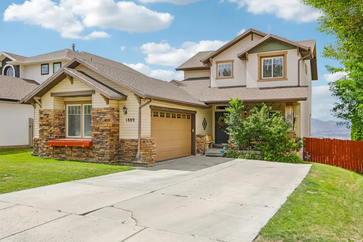 Multi-level residence featuring a two-car garage with a wood-finish door, stone veneer accents, and siding