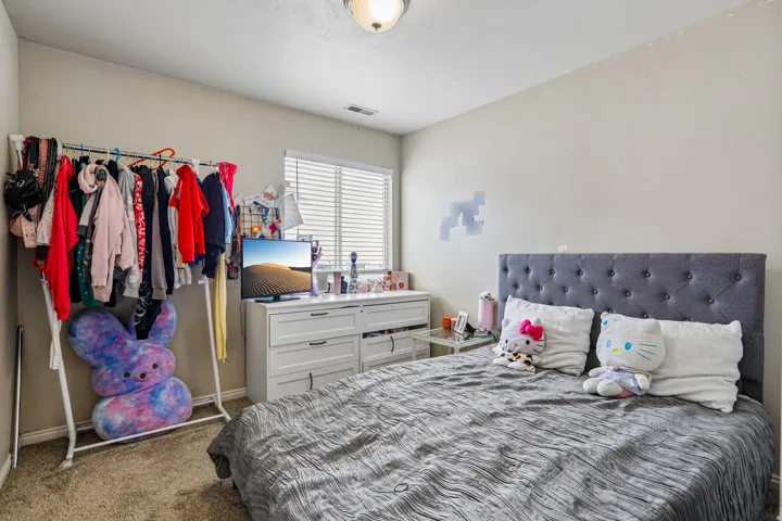Bedroom featuring light neutral wall tones and textured carpeting