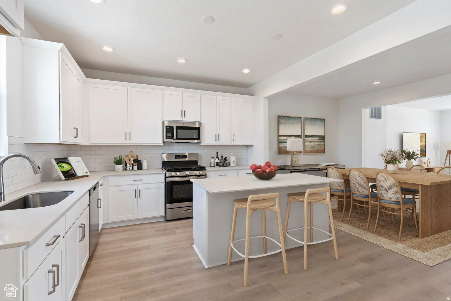 Modern kitchen featuring white cabinetry, stainless steel appliances, light-toned wood-finish flooring, and recessed lighting