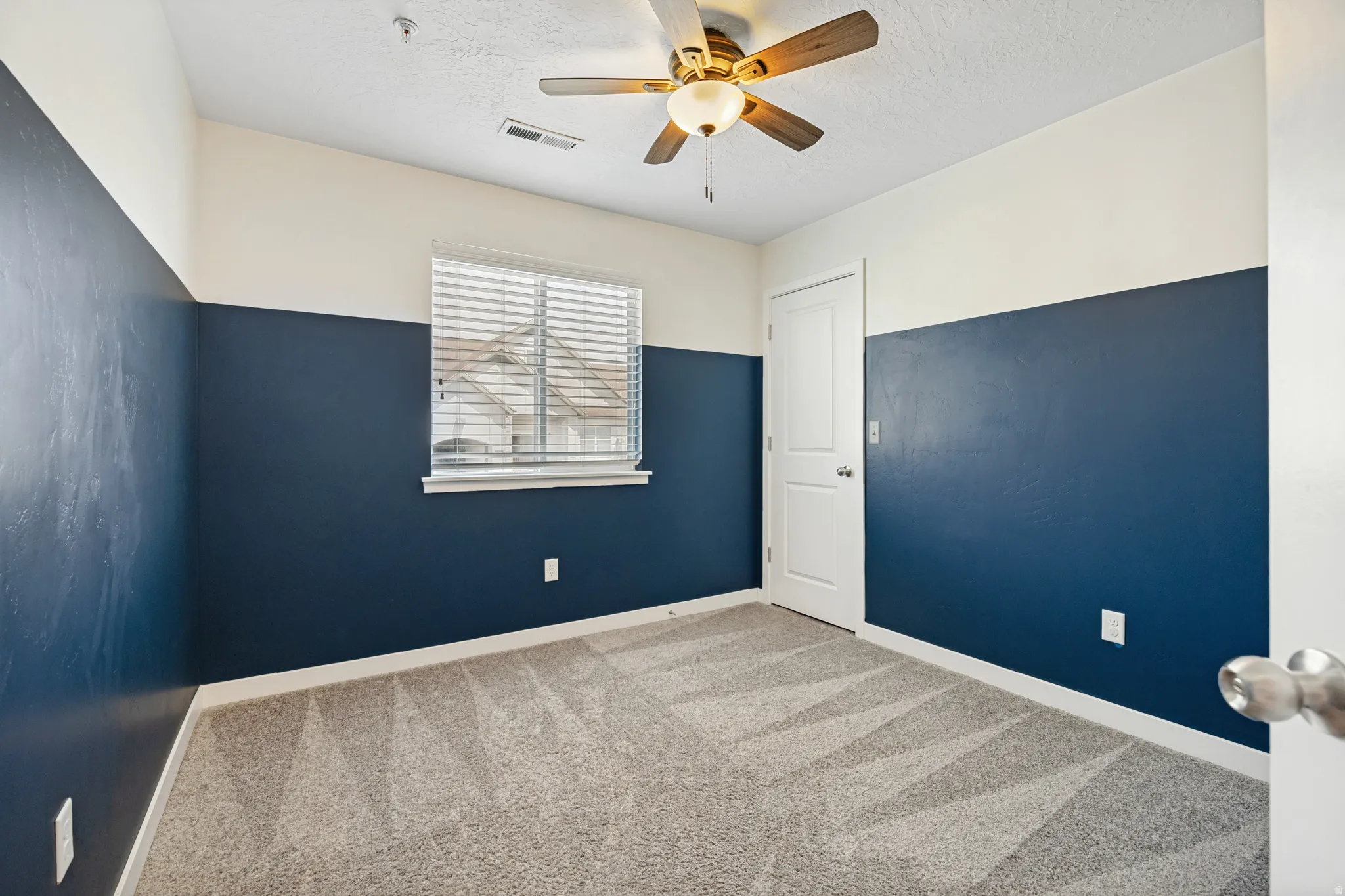 Bedroom featuring two-tone walls, light gray carpeting, a ceiling fan with integrated lighting.