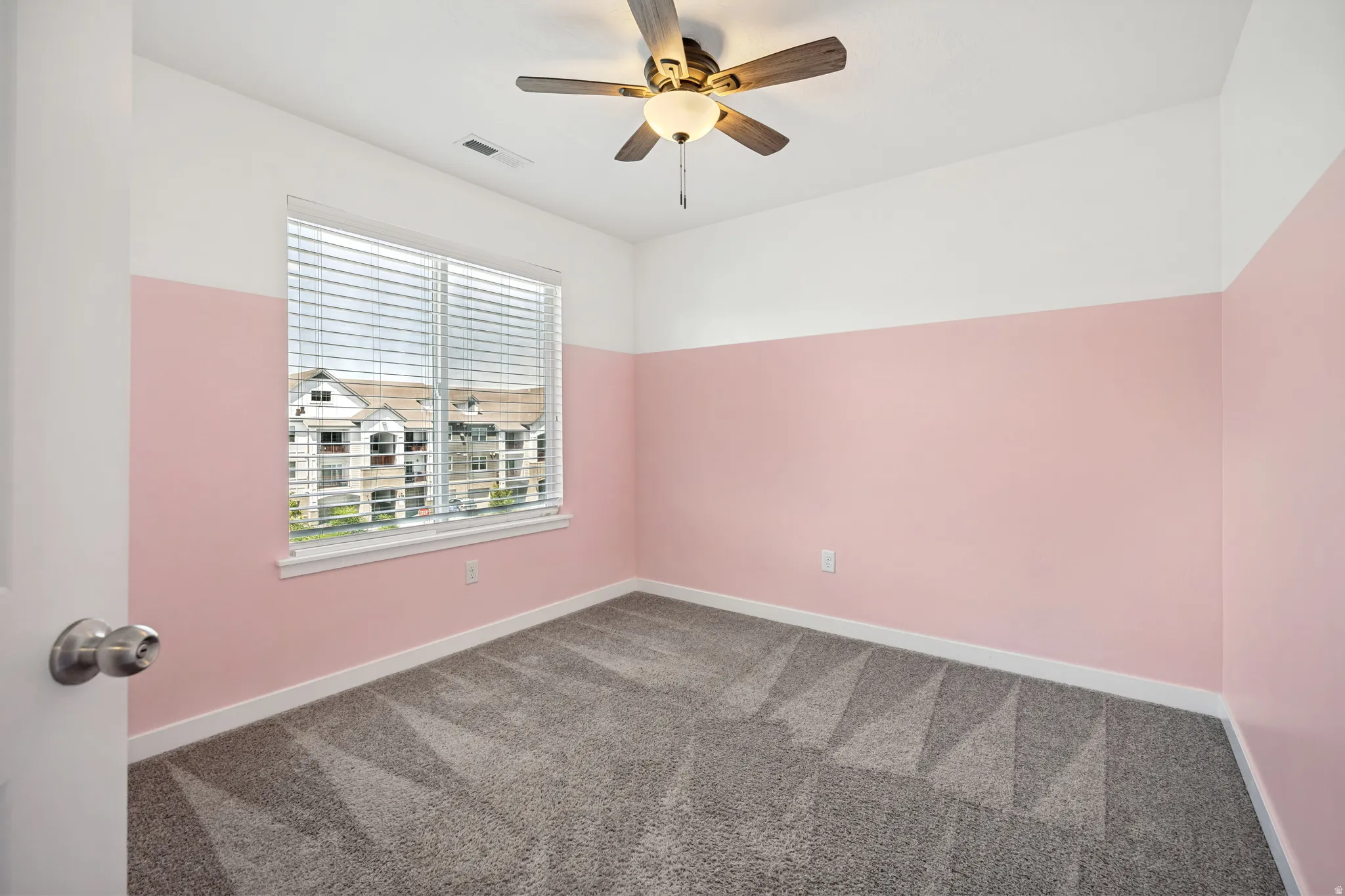Bedroom featuring two-toned walls, light gray carpeting, a ceiling fan with integrated lighting.
