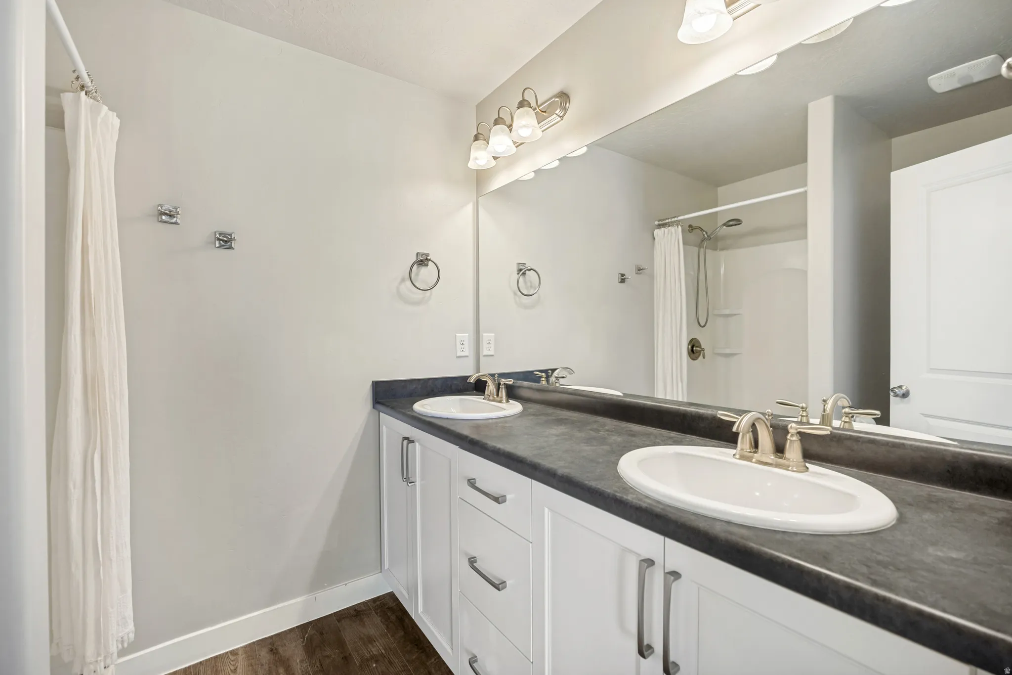 The primary ensuite offers a double sink with fresh white cabinetry and a well-appointed shower.
