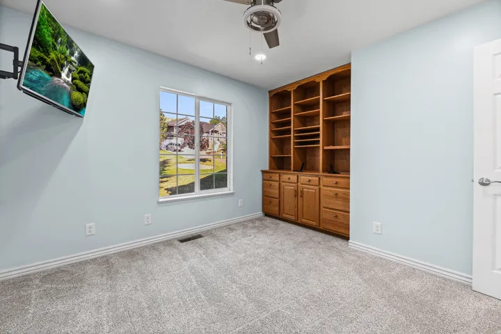 Built-in wood cabinetry with shelving and drawers, light blue walls, and grey carpeted flooring